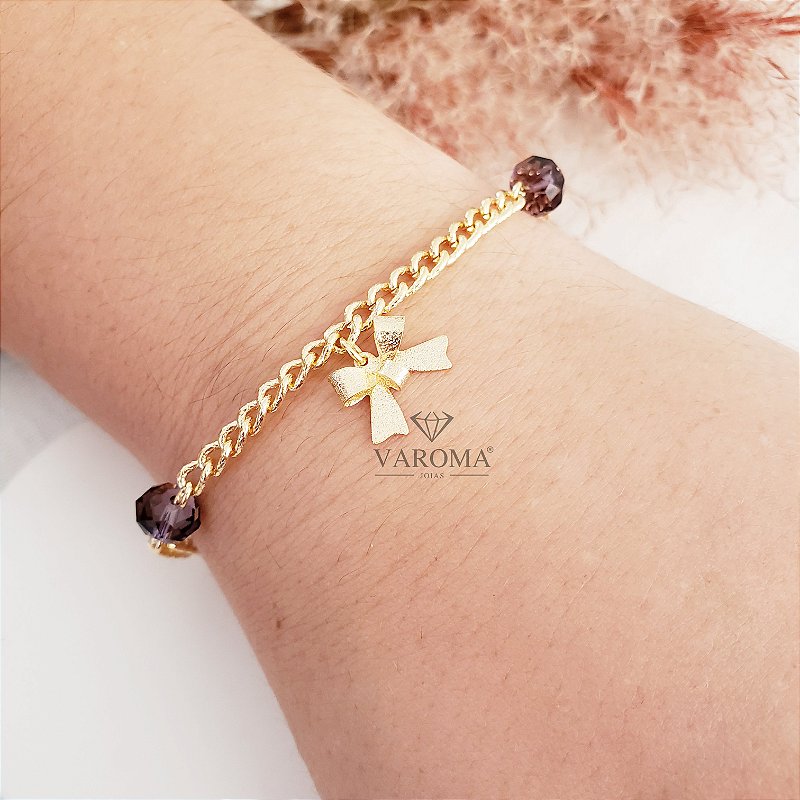 Pulseira com cristais e pingente de lacinho banhada em ouro 18k